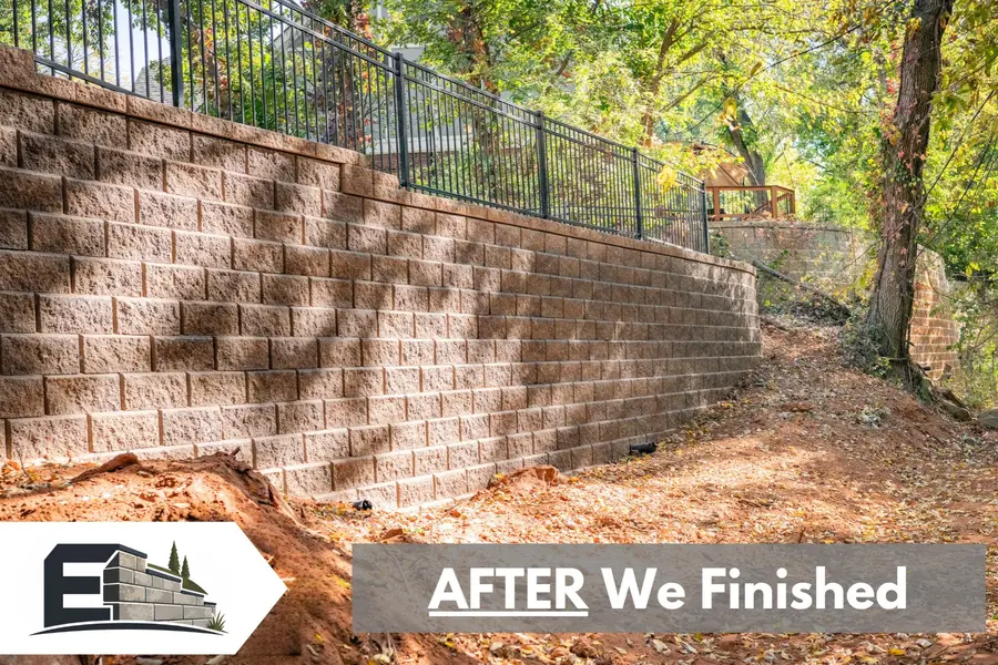 After: new segmental block retaining wall with a metal railing on the same slope