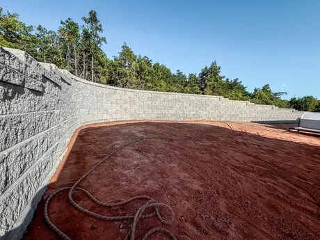 Curved split-face block retaining wall around a graded backyard
