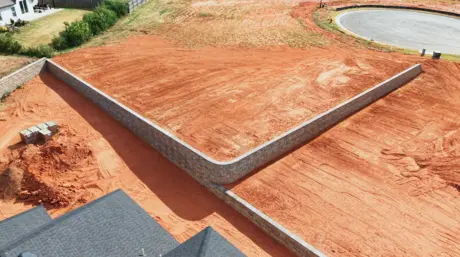 Aerial view of an engineered retaining wall wrapping a graded building pad