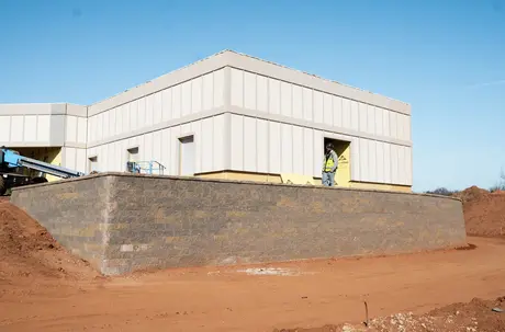Segmental block retaining wall supporting the pad of a commercial building under construction