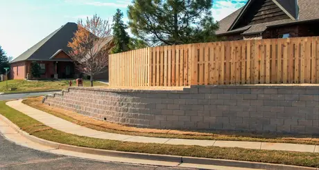 Stepped retaining wall supporting a fenced yard above a neighborhood sidewalk