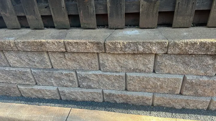 Close-up of split-face block retaining wall courses with a cap layer