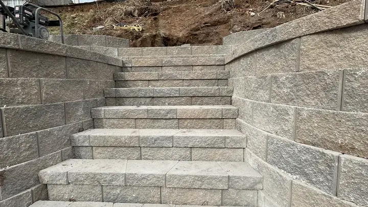New block stairs built between retaining wall tiers leading up a slope