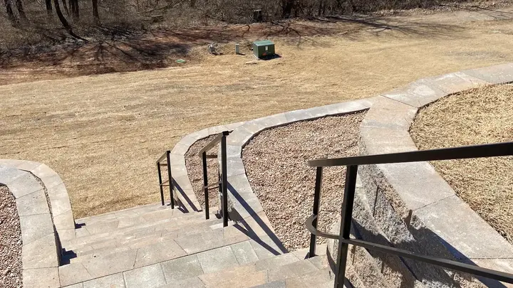 View down new block stairs with metal railings between curved wall tiers