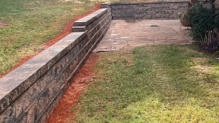 Two-tier retaining wall bordering a backyard patio and lawn