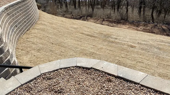 Curved multi-tier retaining wall with fresh sod and gravel planting beds