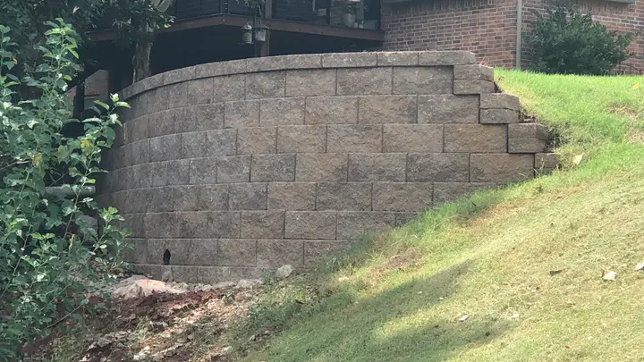Curved block retaining wall holding a slope below a home's deck