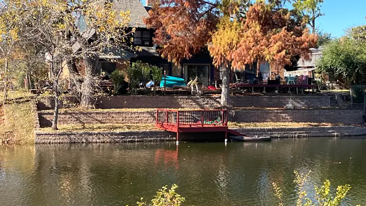 Tiered block retaining walls stepping down to a pond with a rebuilt red dock